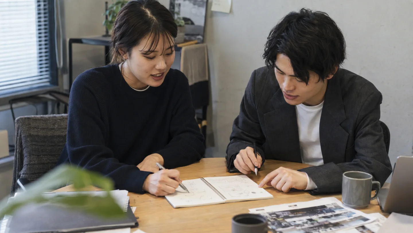 二人でノートにアイデアを書きながら相談するイメージ